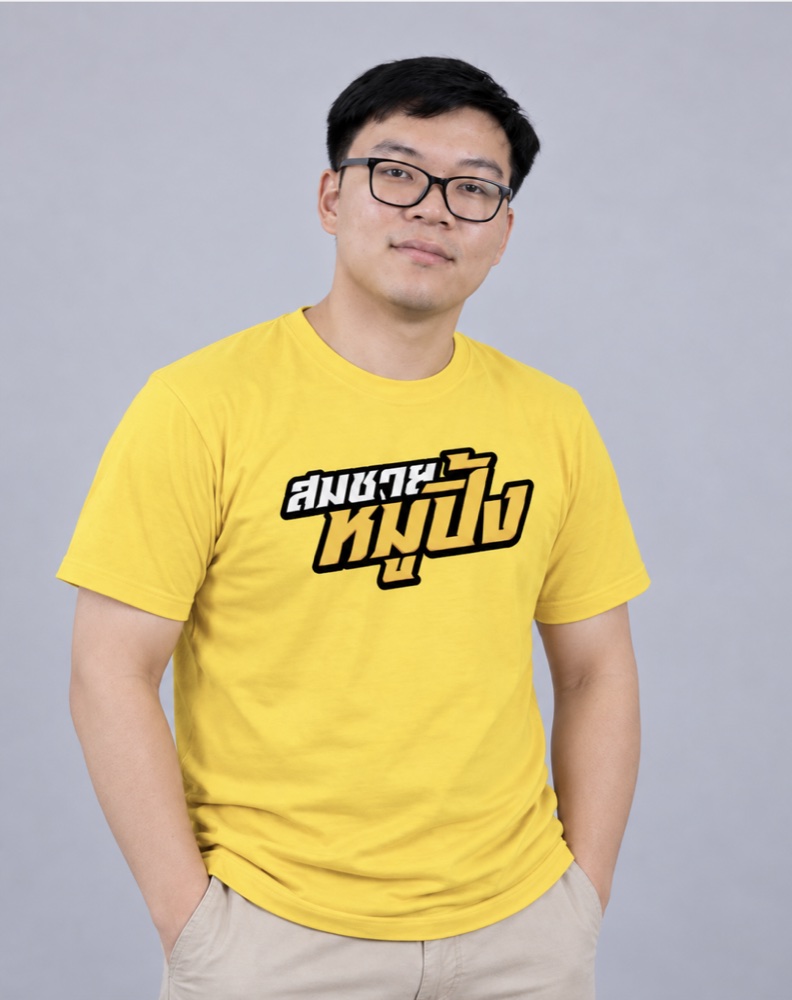 มังกร ผู้ร่วมก่อตั้งสมชายหมูปิ้ง สวมแว่นและเสื้อเหลืองลายโลโก้ร้าน